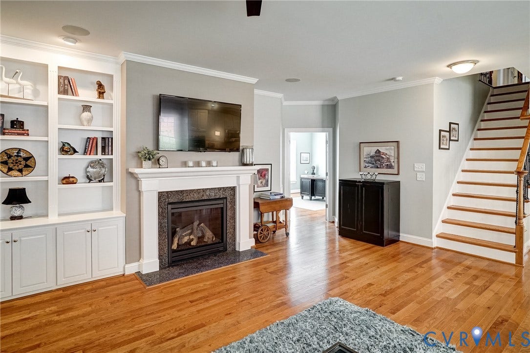 4938 Grey Oaks Villas Drive, Glen Allen, VA 23059 Hardwood flooring throughout, built-in cabinetry with shelving, fireplace with a stone surround and hearth, and a staircase with wood treads and a wood railing