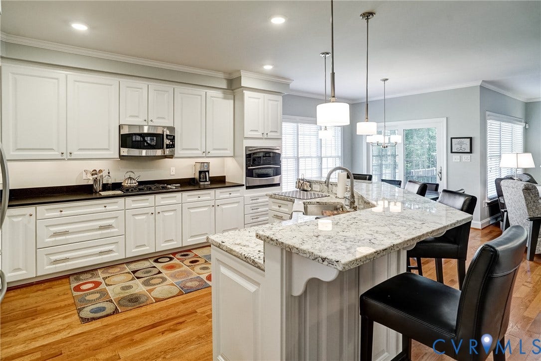 4938 Grey Oaks Villas Drive, Glen Allen, VA 23059 White cabinetry, stainless steel appliances, granite countertops, hardwood flooring, and pendant lighting