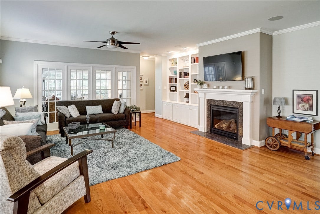 4938 Grey Oaks Villas Drive, Glen Allen, VA 23059 Hardwood flooring throughout, a ceiling fan, built-in shelving, a fireplace with a stone surround, and French doors