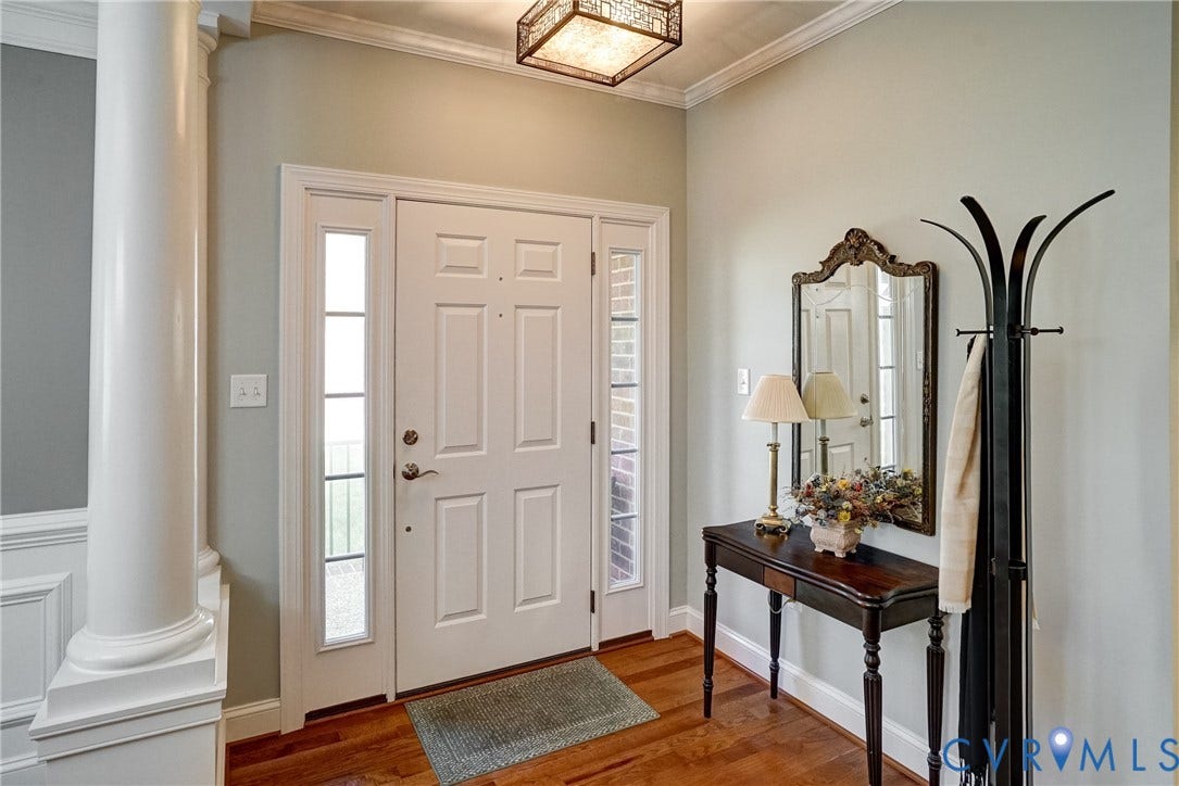 4938 Grey Oaks Villas Drive, Glen Allen, VA 23059 Solid wood flooring, paneled front door with sidelights, decorative ceiling light fixture, white crown molding, and wainscoting