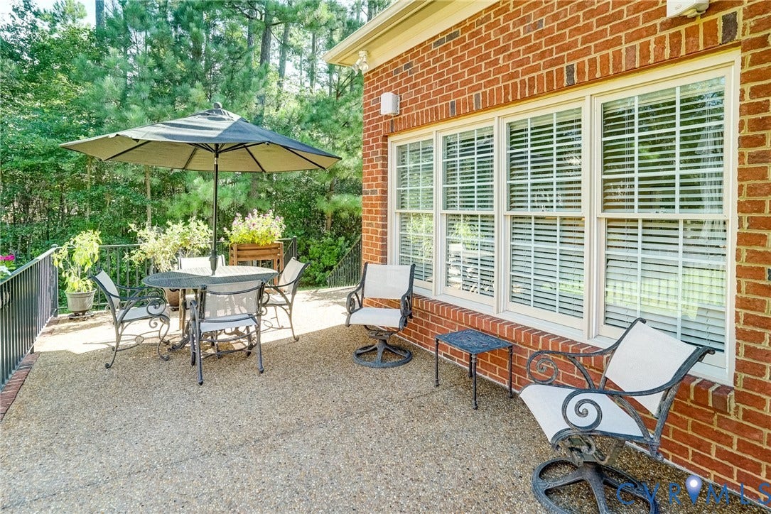 4938 Grey Oaks Villas Drive, Glen Allen, VA 23059 Brick exterior with a textured patio surface, black metal railing, and multiple windows with blinds