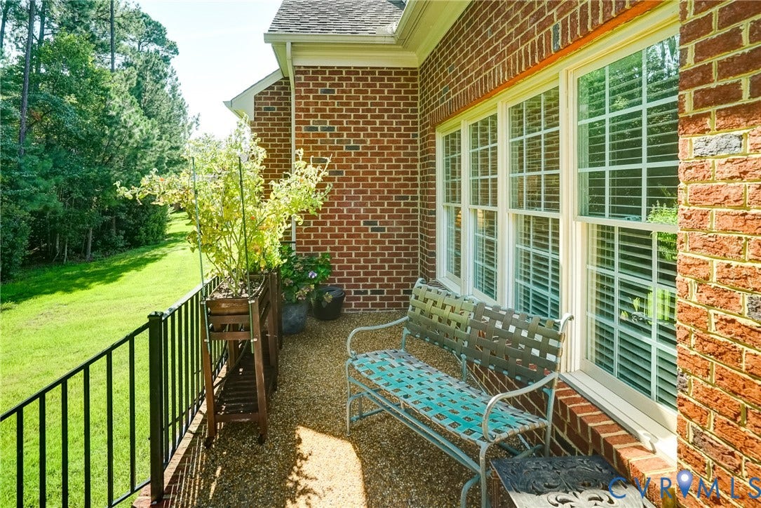 4938 Grey Oaks Villas Drive, Glen Allen, VA 23059 Brick exterior with multiple windows, a gravel-finished patio, and a black metal railing