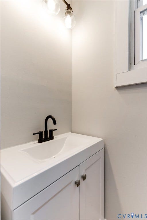 White vanity with integrated sink, matte black faucet, and clear glass globe light fixture
