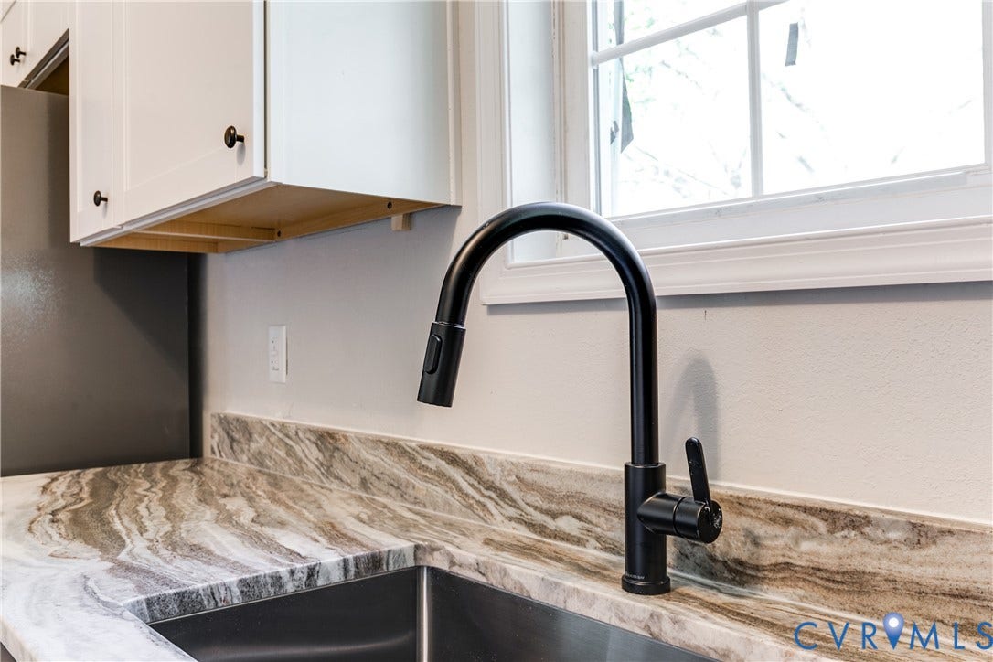 White cabinetry with dark hardware, a window with grid detailing, and a black gooseneck faucet