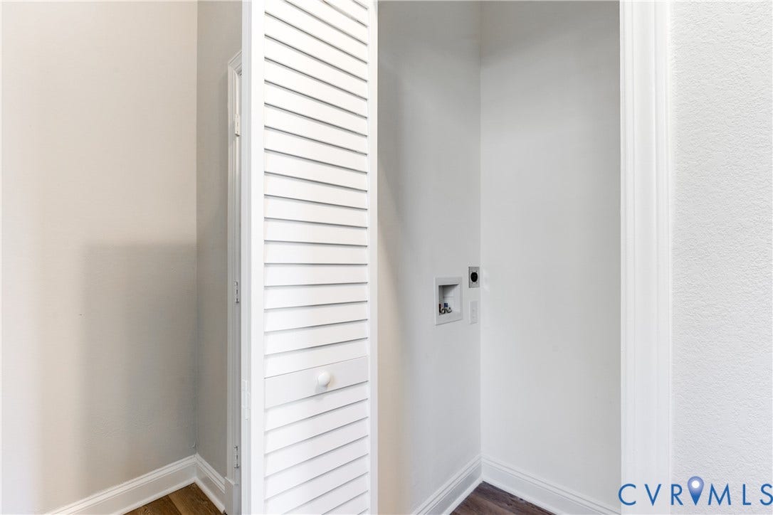 Utility space featuring wood-finish flooring, white walls, and a louvered bi-fold door