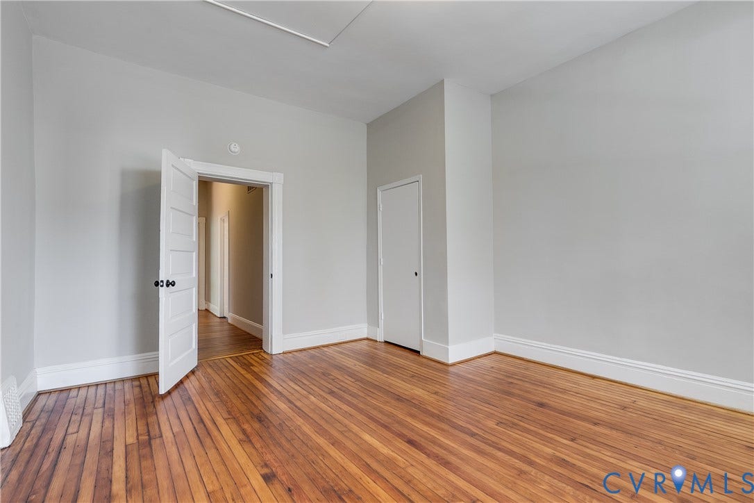 Wood-finish flooring with white trim and a neutral wall color