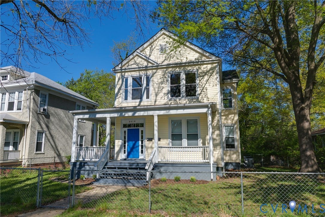 Two-story residence featuring light-colored siding, a covered front porch, and a vibrant blue entry door
