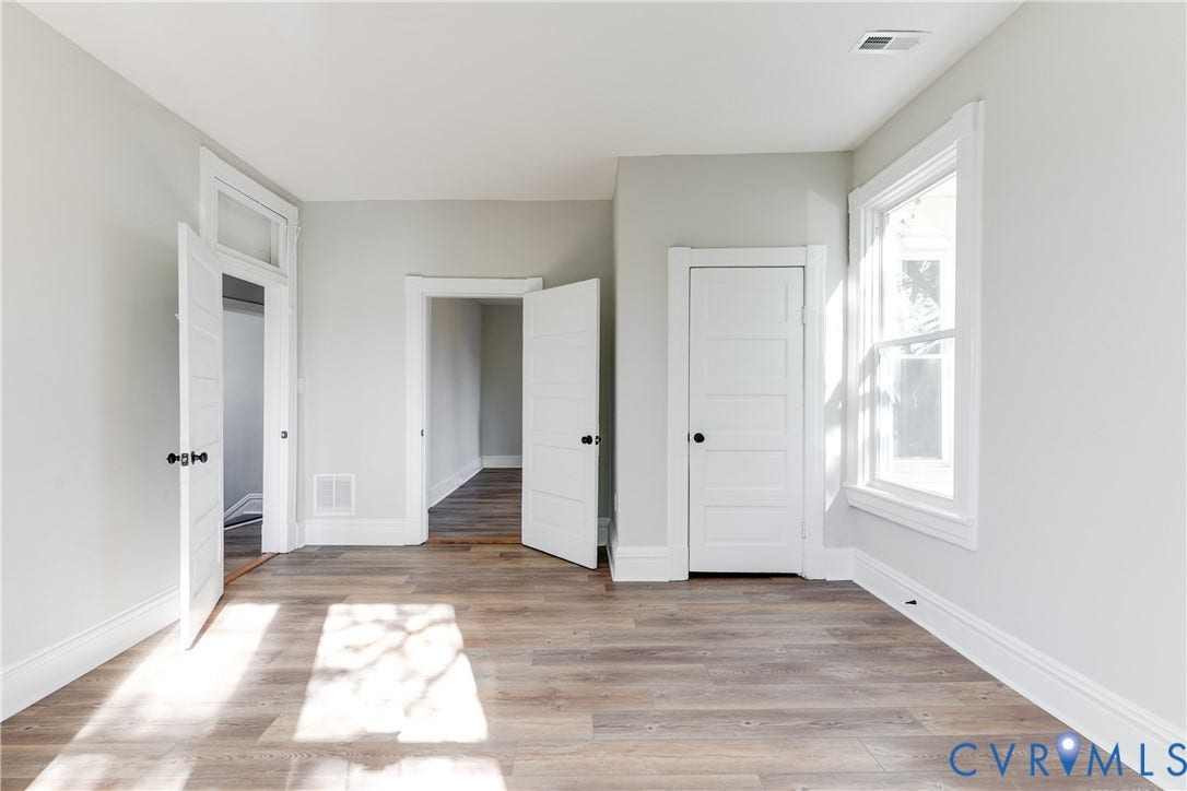 Wood-finish flooring with white trim and multiple doorways