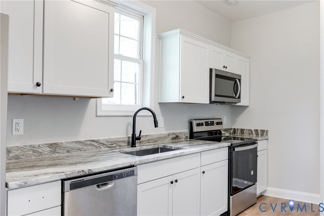 White shaker cabinetry, stainless steel appliances, stone countertops, black gooseneck faucet, and wood-finish flooring