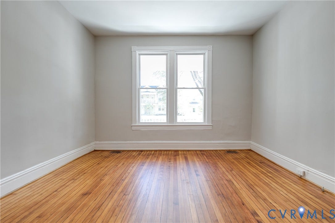 Wood-finish flooring, white window trim, and light gray wall paint