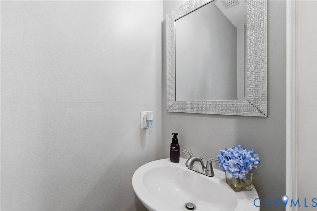 4429 Crown Squire Road, Henrico, VA 23231 White wall-mounted sink with brushed nickel faucet, complemented by a decorative framed mirror