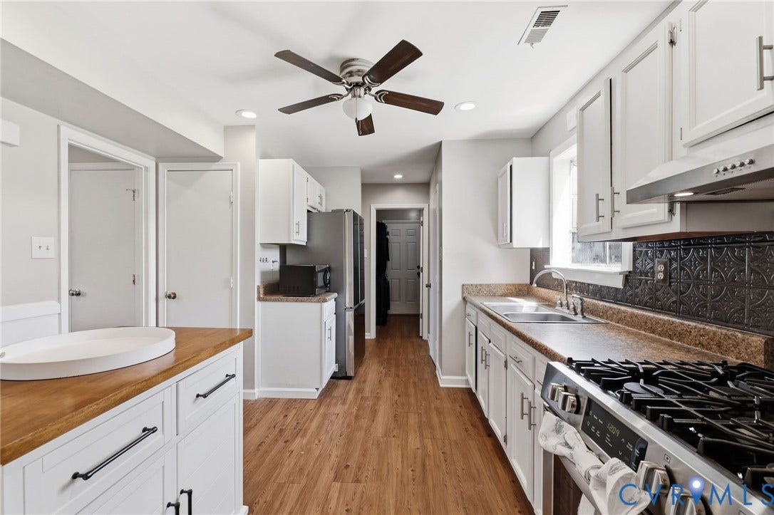 4429 Crown Squire Road, Henrico, VA 23231 Galley kitchen featuring wood-finish flooring, white cabinetry, dark patterned backsplash, stainless steel appliances, and a ceiling fan