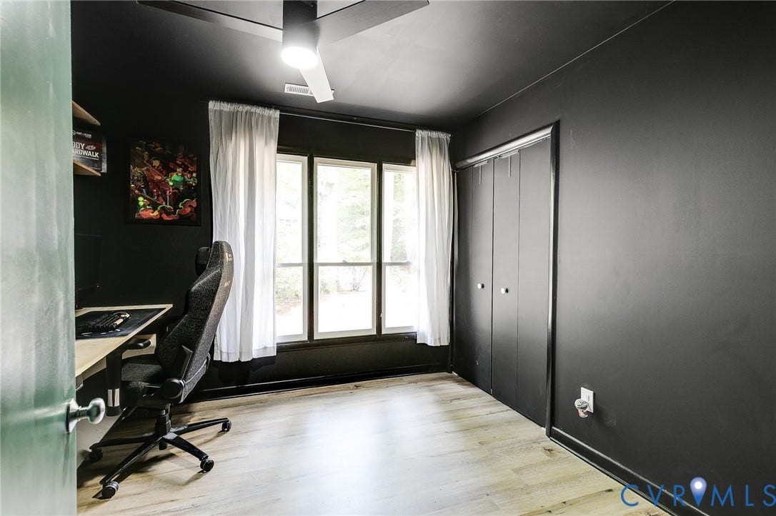 Wood-finish flooring, dark wall finishes, an integrated ceiling fan with lighting, multiple windows, and a bi-fold closet