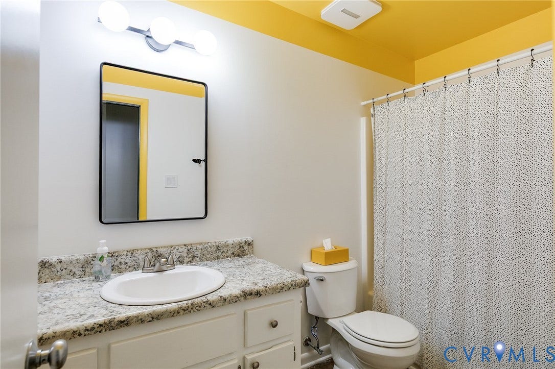 White vanity with an undermount sink and a speckled countertop