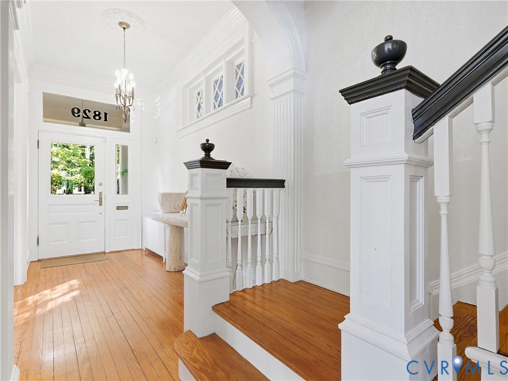 1829 Floyd Avenue, The Fan, Richmond, VA 23220 Hardwood flooring, 10+ ft ceilings, white paneled doors, staircase with painted newel posts, decorative archway, and an ornate ceiling medallion