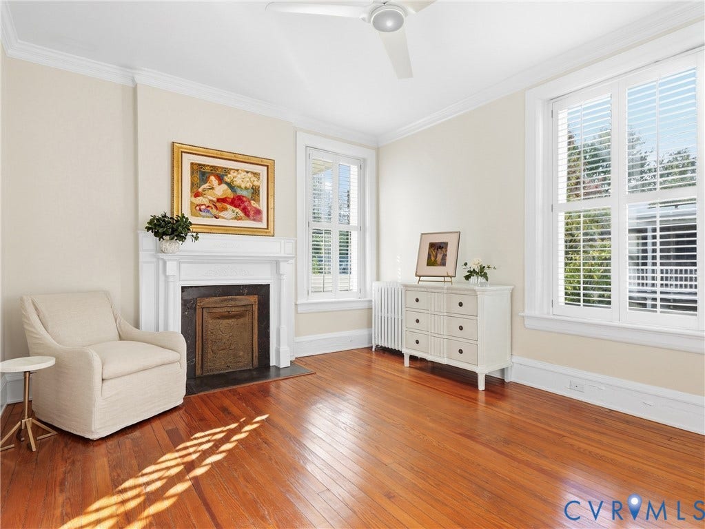 1829 Floyd Avenue, The Fan, Richmond, VA 23220 Hardwood flooring with a decorative fireplace and white mantel, crown molding, and multiple windows with plantation shutters