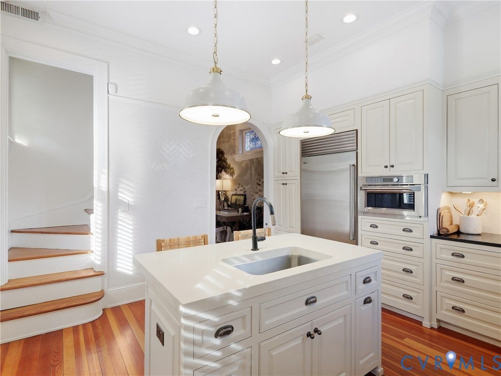 1829 Floyd Avenue, The Fan, Richmond, VA 23220 Gourmet kitchen with white cabinetry, built-in stainless steel appliances, a center island with an integrated sink, and pendant lighting