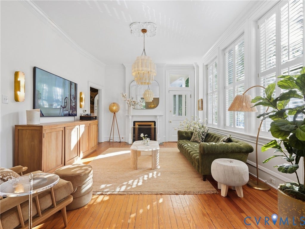 1829 Floyd Avenue, The Fan, Richmond, VA 23220 Warm-toned wood flooring, multiple tall windows with plantation shutters, crown molding, a decorative fireplace, and a light-toned chandelier