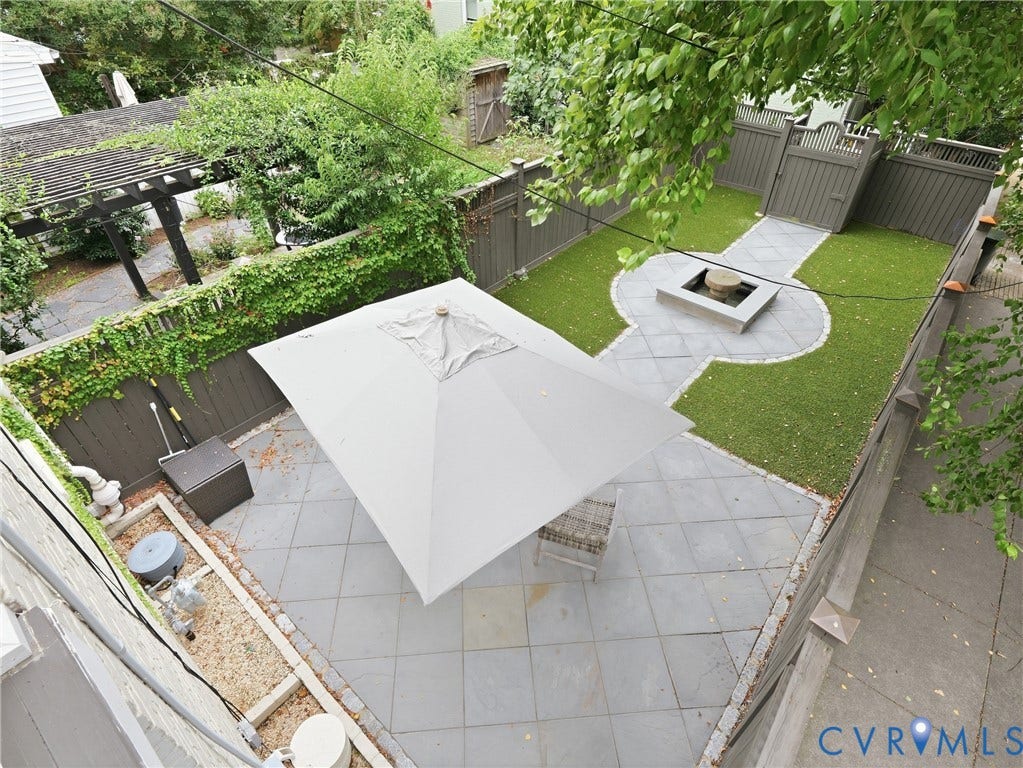 1829 Floyd Avenue, The Fan, Richmond, VA 23220 Stone tile patio with a large umbrella, artificial turf, stone fire pit, and privacy fencing