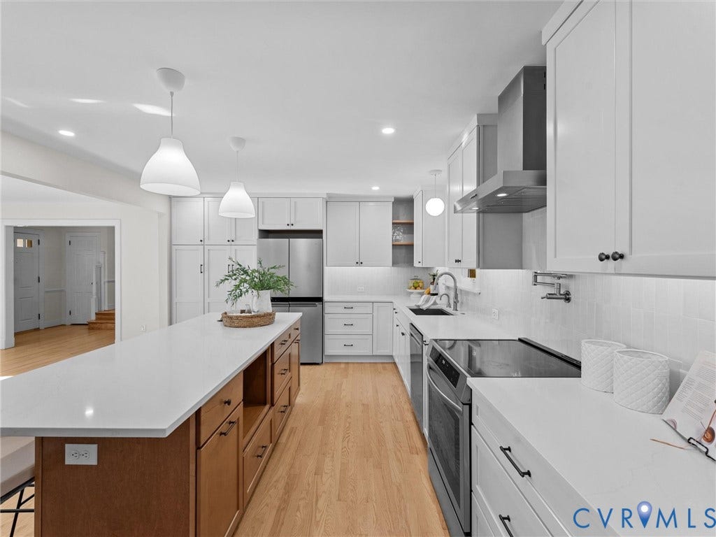 3436 Kenmore Road, Richmond, VA 23225 Kitchen featuring a large island with a light-toned countertop, white cabinetry with dark hardware, stainless steel appliances, wood-finish flooring, and pendant lighting