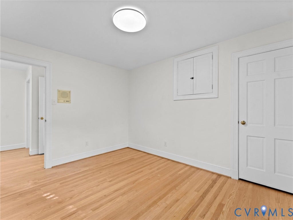 3436 Kenmore Road, Richmond, VA 23225 Wood-finish flooring, white walls, flush-mount ceiling light, white paneled door, and built-in wall cabinet