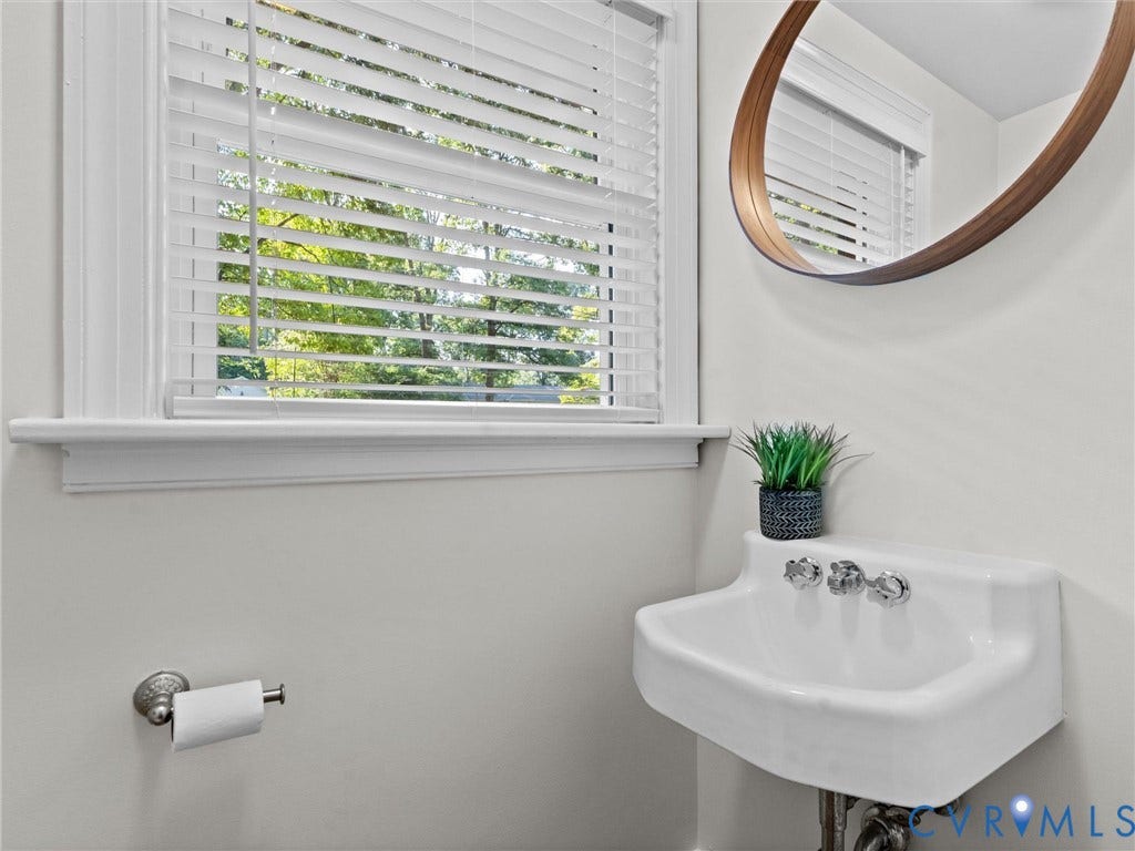 3436 Kenmore Road, Richmond, VA 23225 Wall-mounted sink with chrome fixtures, window with blinds, and a framed mirror