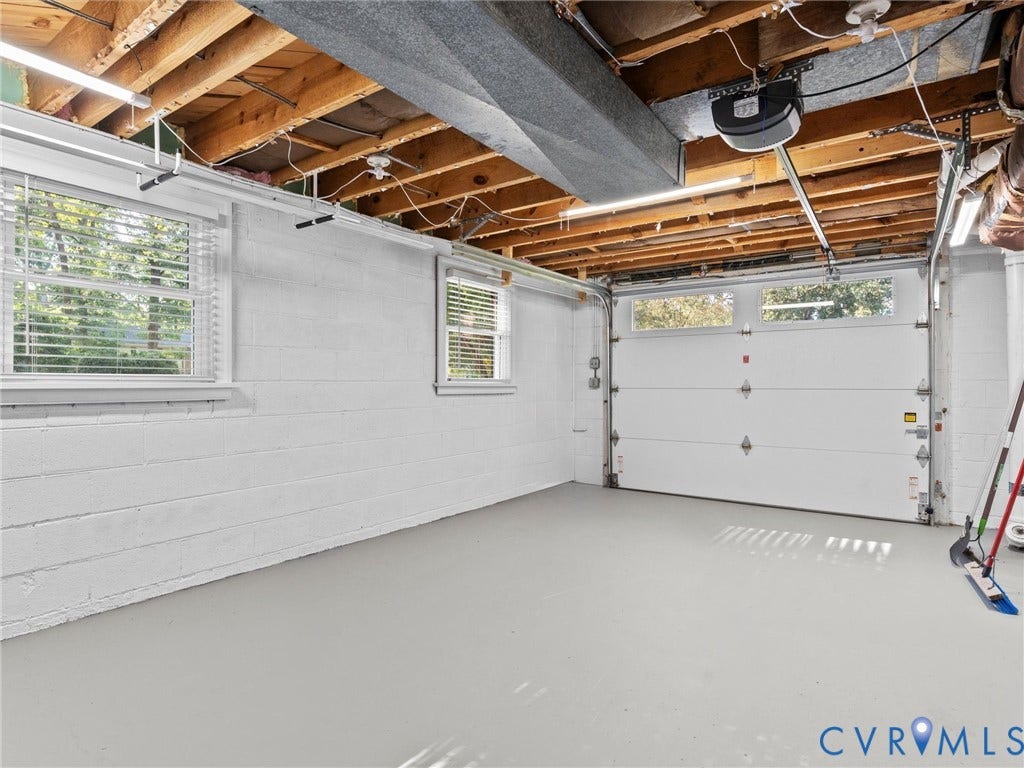 3436 Kenmore Road, Richmond, VA 23225 Two transom windows, white paneled garage door, exposed wood ceiling beams, painted block walls, and overhead lighting