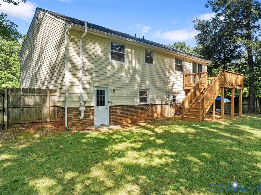 Expansive lawn with a wooden privacy fence, featuring a two-story wood deck and brick foundation