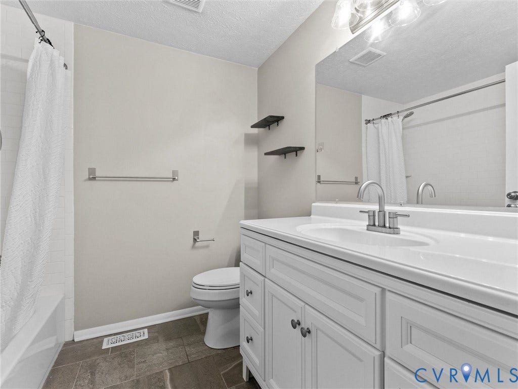 White vanity with panel-front cabinetry, an integrated sink, and a large wall-mounted mirror