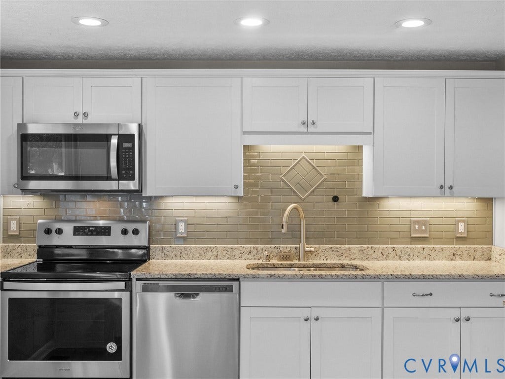 White shaker cabinetry, stainless steel appliances, speckled stone countertops, subway tile backsplash, and recessed lighting