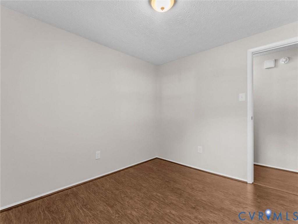 Wood-finish flooring with light-toned walls and a flush-mount ceiling light