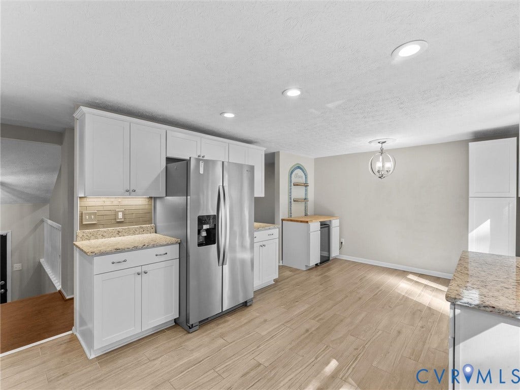 White cabinetry, stainless steel refrigerator, tile backsplash, granite-style countertops, wood-finish flooring