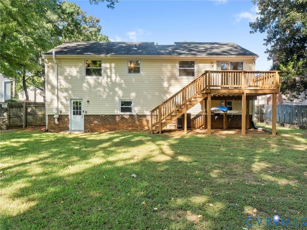 Rear exterior featuring a wood deck with stairs, a white rear entry door, and light-colored siding