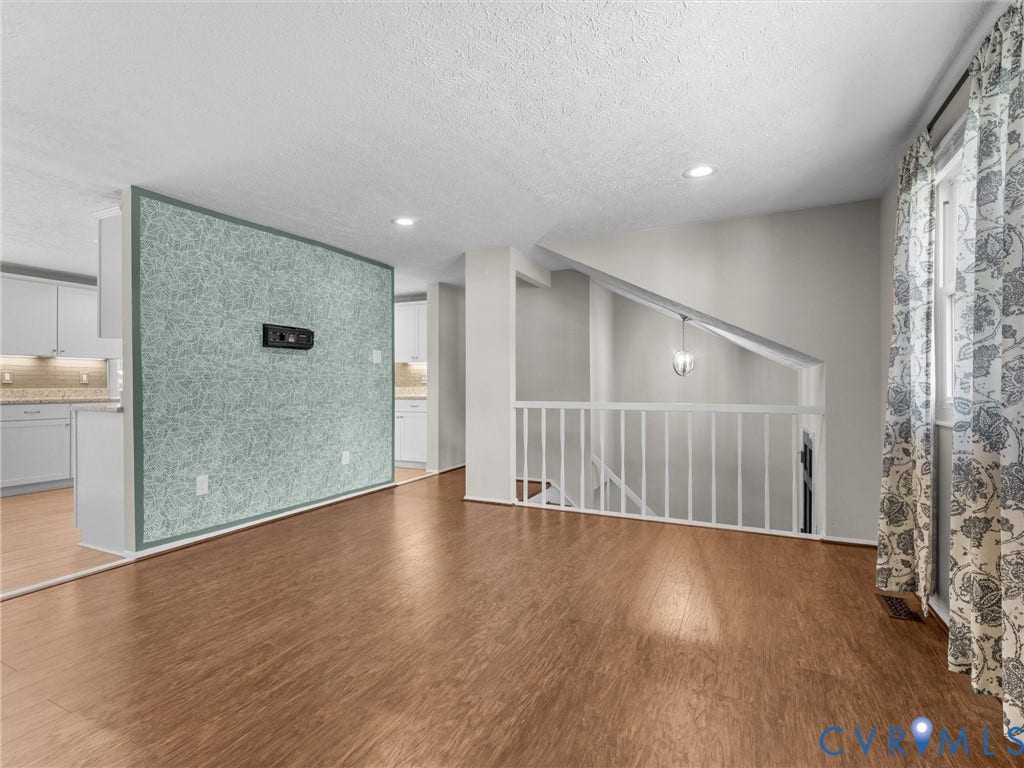 Wood-finish flooring throughout, recessed lighting, and a partial wall with textured wallpaper