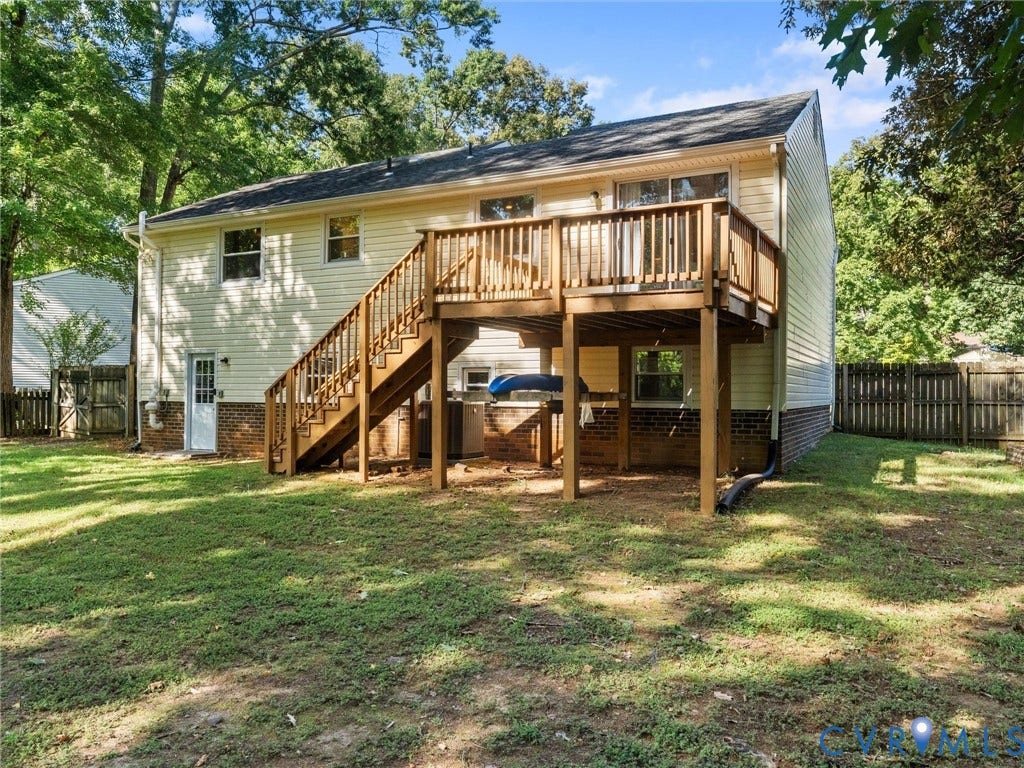 Rear exterior with wood siding, a multi-level wood deck, and a brick foundation