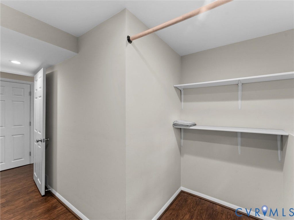 Wood-finish flooring, recessed lighting, white interior door, and built-in closet shelving with hanging rod
