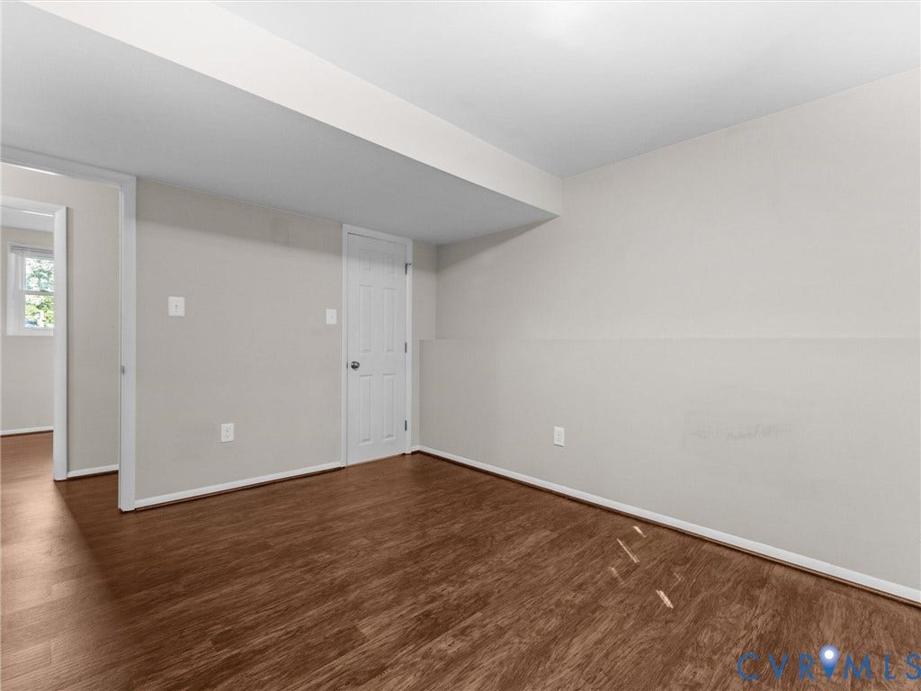 Wood-finish flooring, light grey wall paint, and white trim throughout