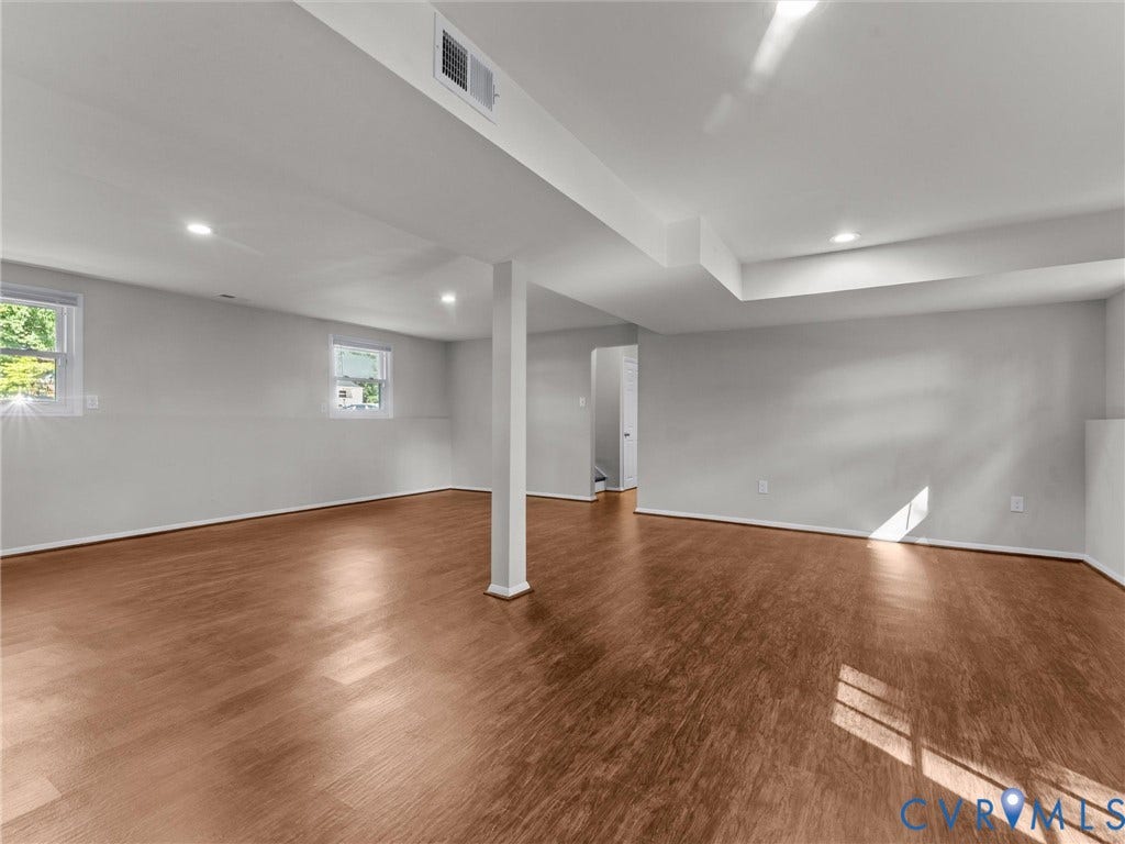 Open-concept room featuring wood-finish flooring, recessed lighting, and multiple windows