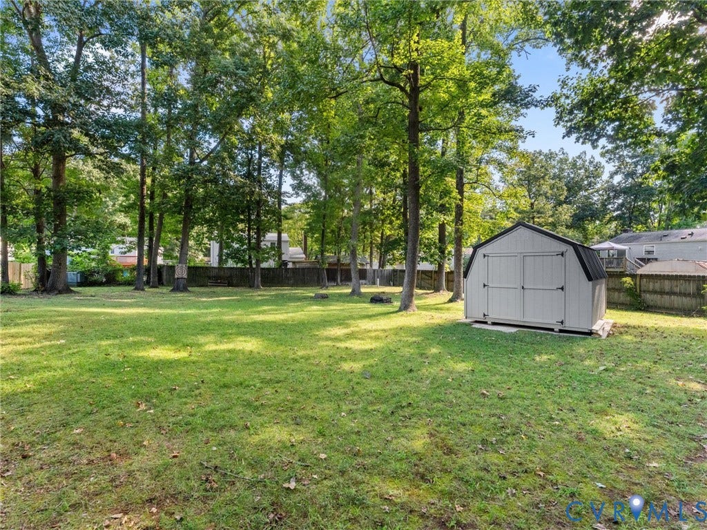 Expansive green lawn with mature trees and a detached shed featuring a gambrel roof and double doors