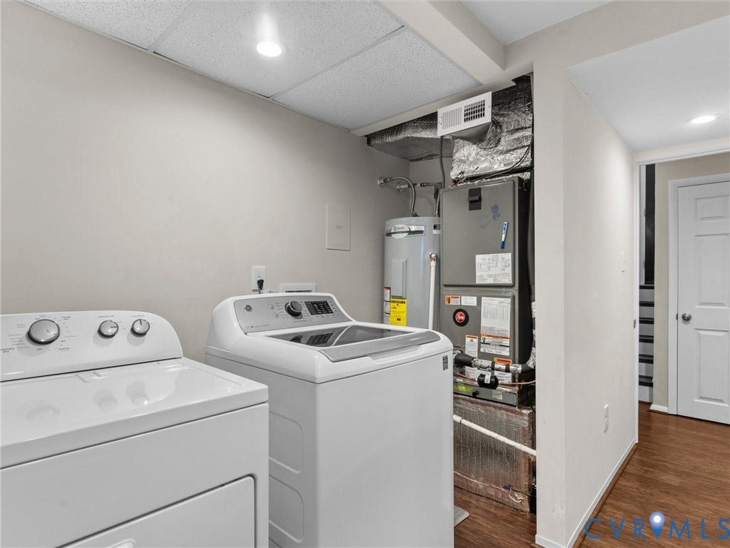 Dedicated utility area featuring a water heater, furnace, and wood-finish flooring