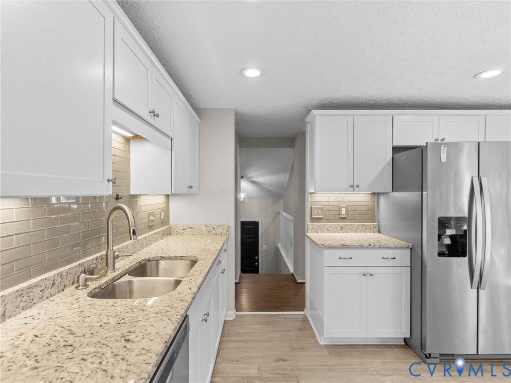 White shaker-style cabinetry with integrated under-cabinet lighting, granite countertops, and a subway tile backsplash