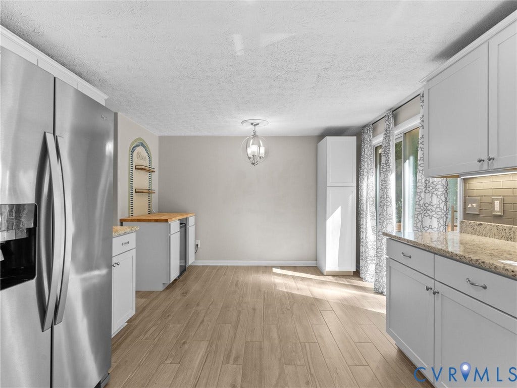 Kitchen with wood-finish flooring, white cabinetry, granite-style countertops, and a subway tile backsplash
