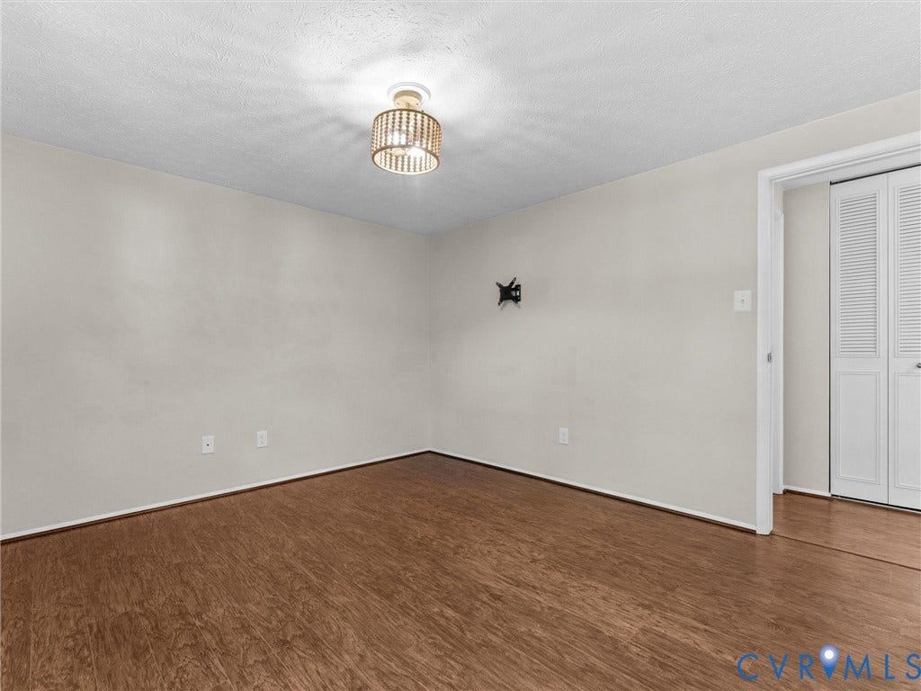 Wood-finish flooring throughout, neutral wall tones, and a modern ceiling light fixture
