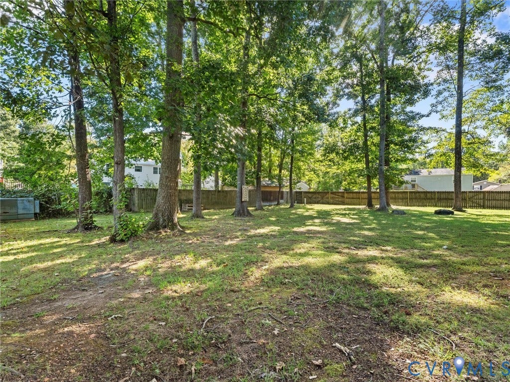 Expansive rear yard with mature trees and a wood privacy fence