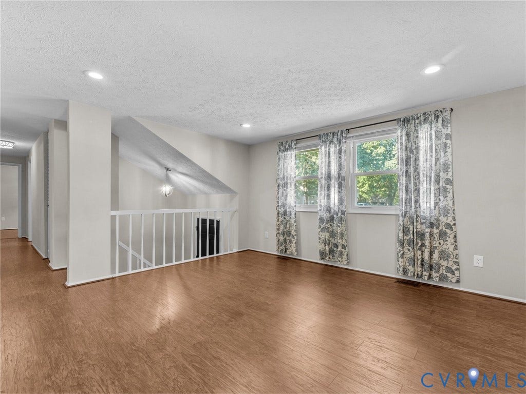 Spacious room with wood-finish flooring, recessed lighting, and large windows