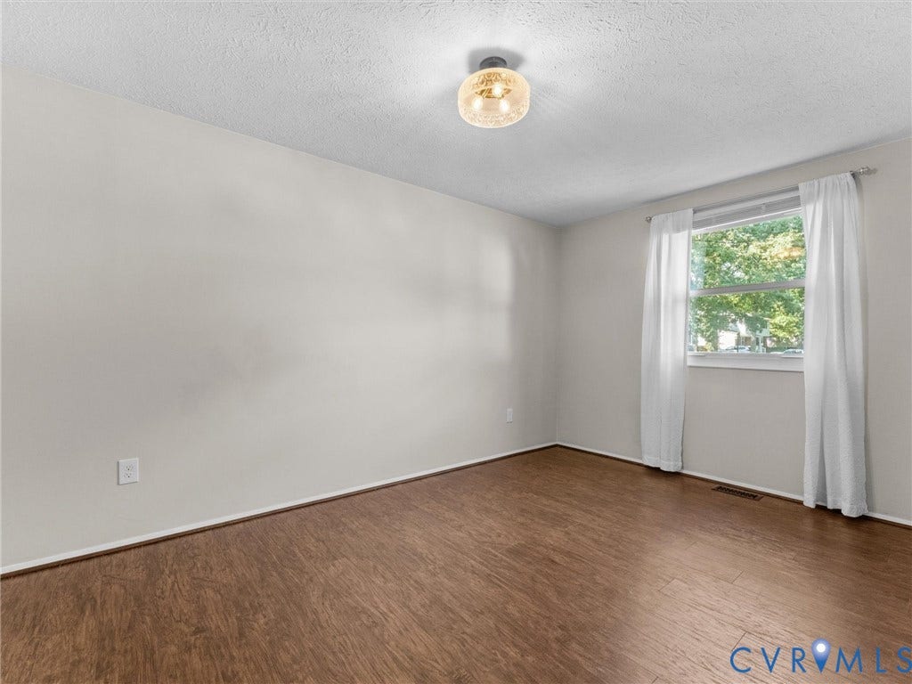 Wood-finish flooring, neutral wall tones, window with natural light, and a decorative ceiling light fixture