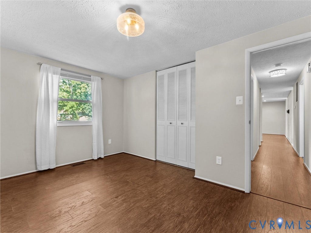 Wood-finish flooring, white bifold closet doors, and flush-mount ceiling light fixture