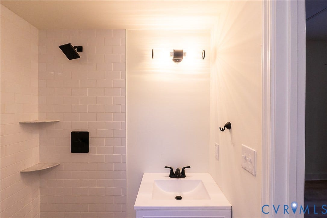 2813 Burfoot Street, Richmond, VA 23224 White subway tile shower with two built-in corner shelves and a matte black rain shower head
