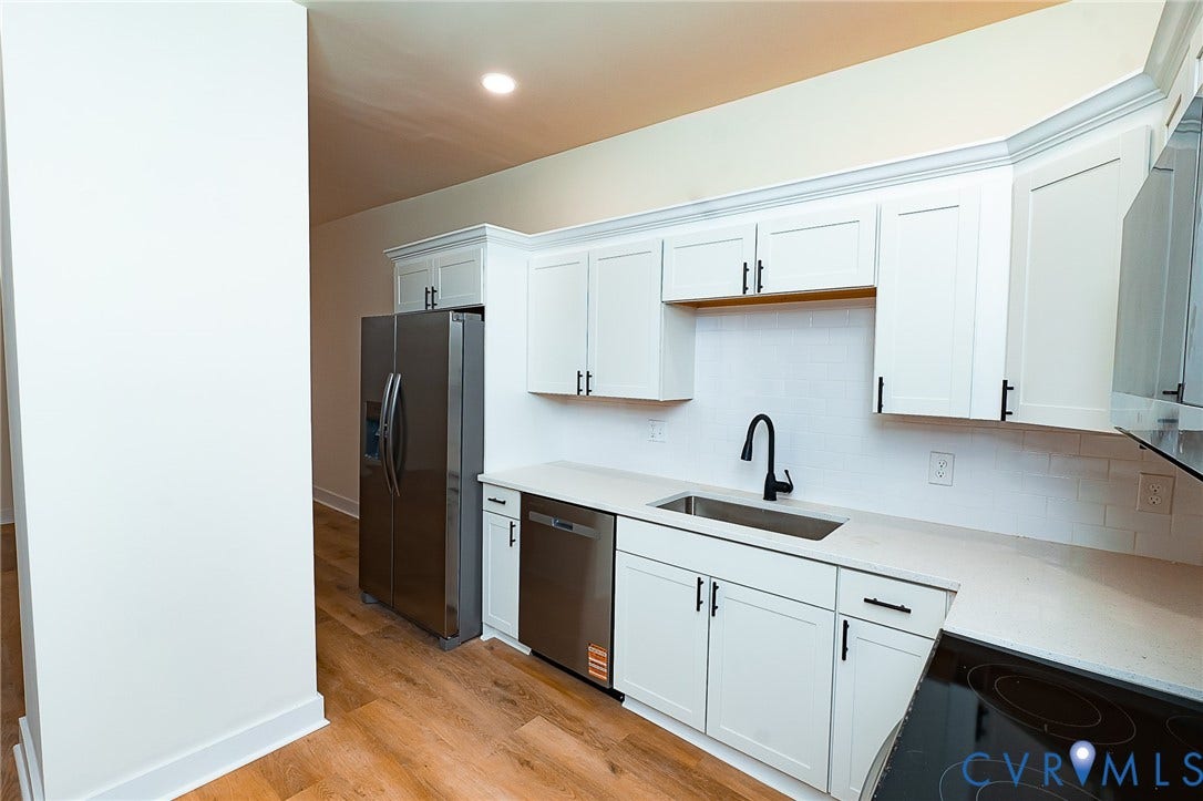 2813 Burfoot Street, Richmond, VA 23224 Kitchen featuring white shaker cabinetry, stainless steel appliances, light-toned countertops, subway tile backsplash, and wood-finish flooring