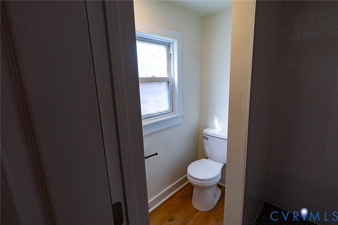 2813 Burfoot Street, Richmond, VA 23224 White toilet with a window, LVP flooring, and dark tile wall